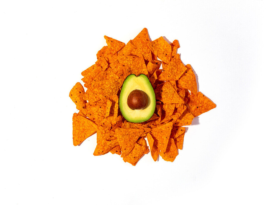 Draufsicht auf eine halbe frische Avocado auf einem Stapel knuspriger Tortilla-Chips auf weißem Hintergrund