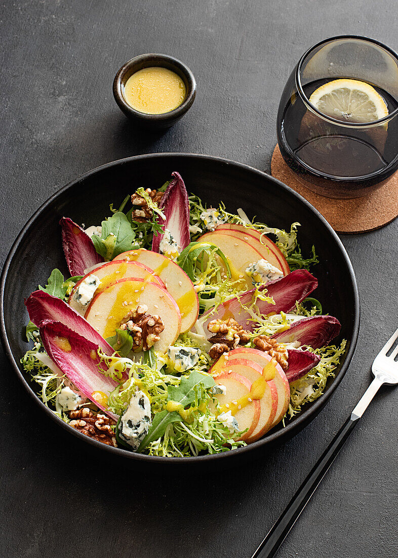 From above colorful delicious salad with endives, apple and roquefort cheese on dark background