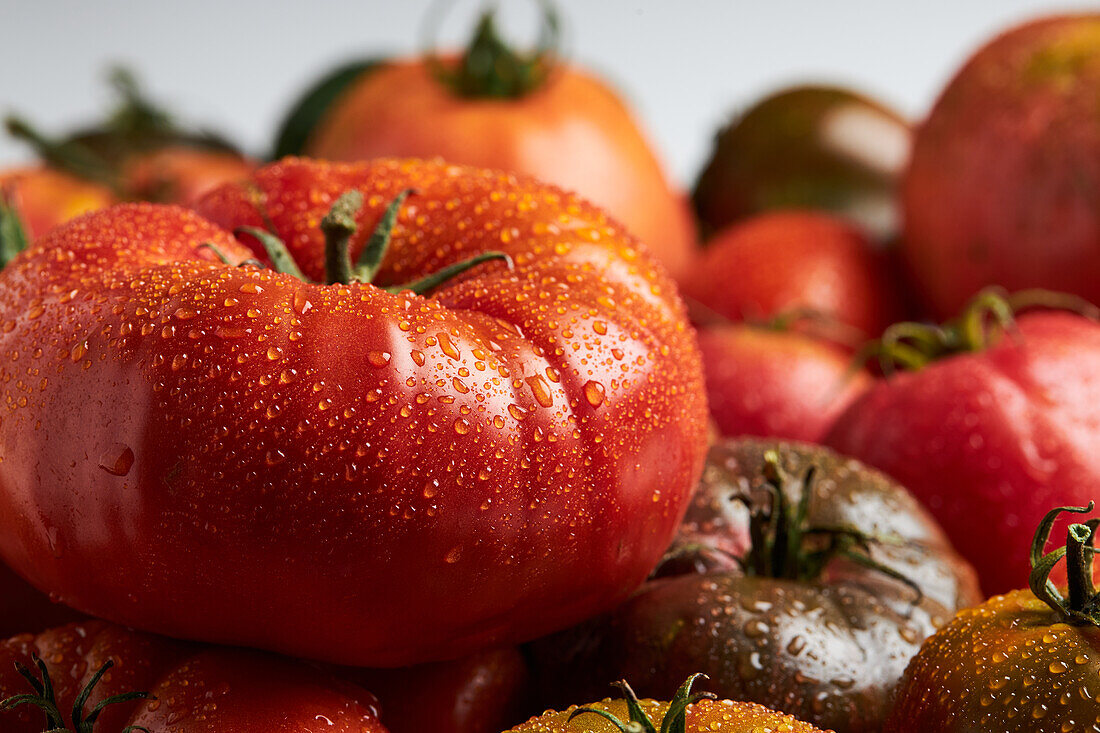 From above of appetizing fresh ripe tomatoes with drops of water with green leaves