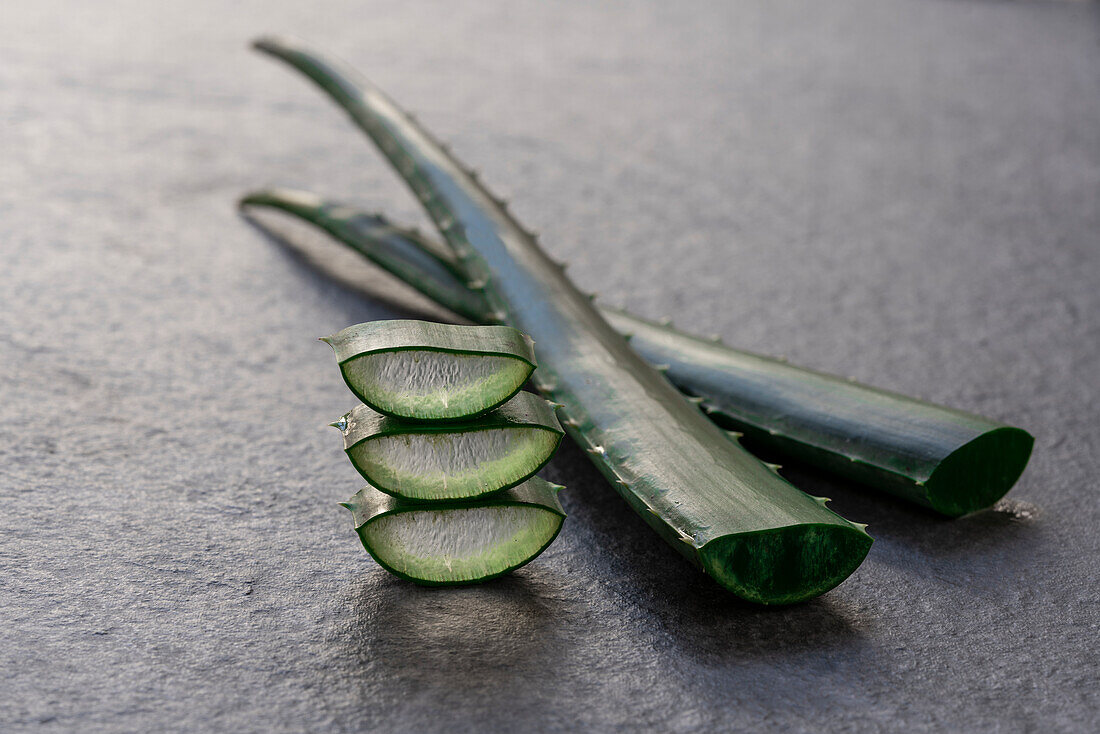 Piece and leaf of green aloe vera placed on gray background in studio