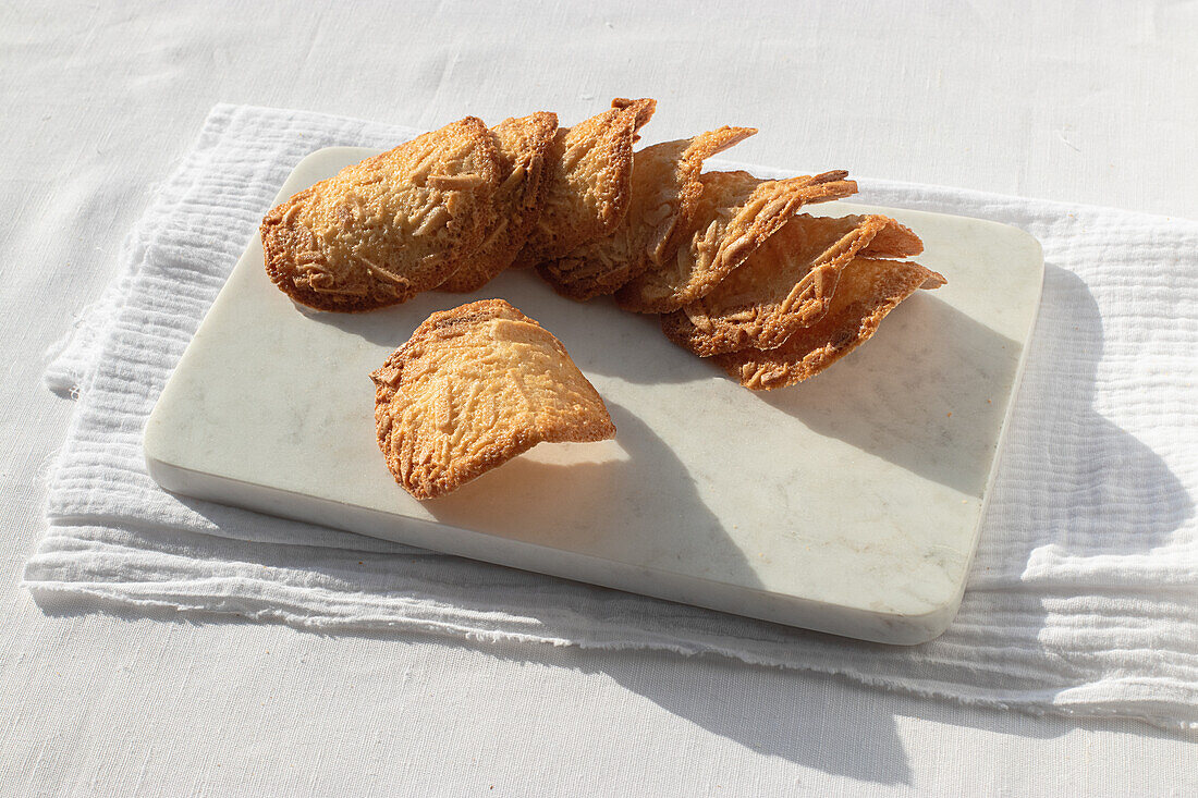 Top view of delicious Almond Tiles cookies placed on plate on tablecloth