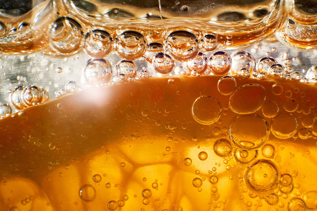 Close-up gin and tonic cocktail with slice of fresh orange bubbling in glass