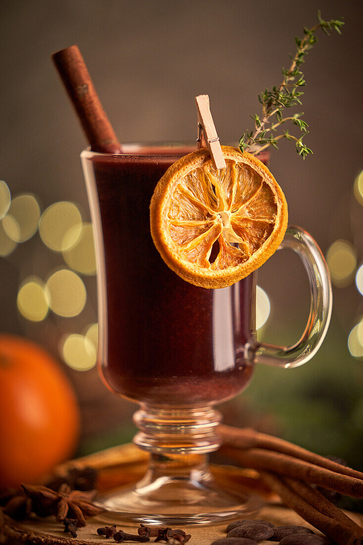 Glühwein oder Weihnachtspunsch, serviert in einem Glasbecher mit getrockneten Orangenscheiben