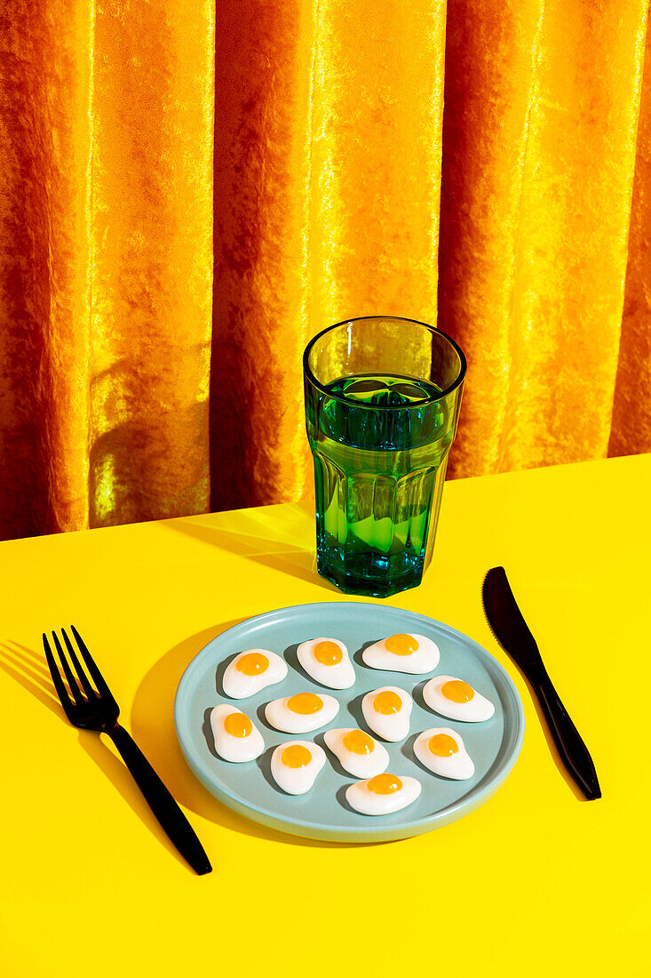 Blick von oben auf Teller mit Gelee-Eiern und Gabel auf gelbem Tisch