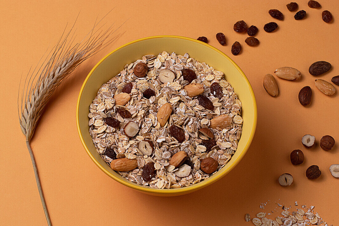 From above crispy granola with nuts in bowl on light table brown background
