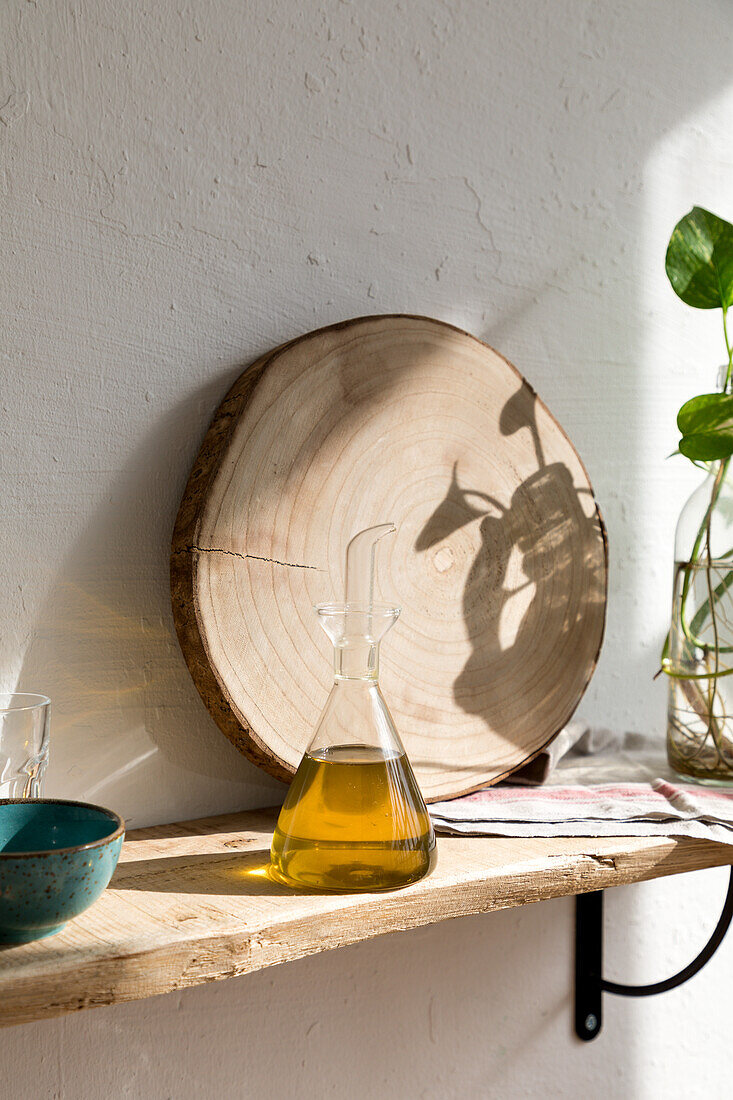 Glass jar with natural aromatic olive oil placed on shelf in home kitchen