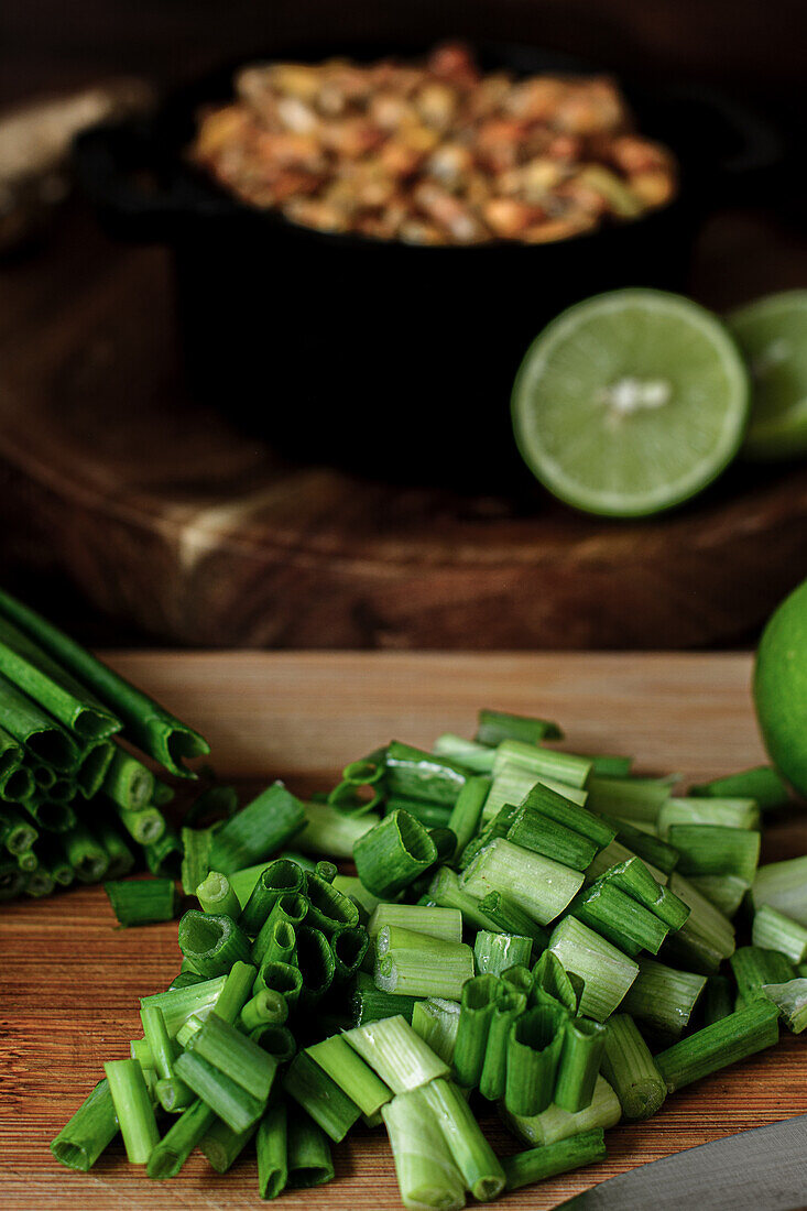 Pile of cut fresh green onion placed on wooden chopping board in domestic kitchen