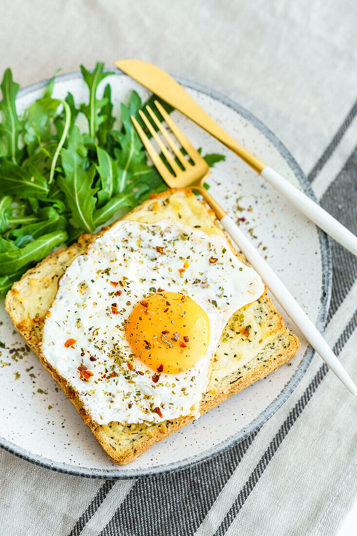 From above toast with eggs and cheese and rocket lettuce served on plate on table background