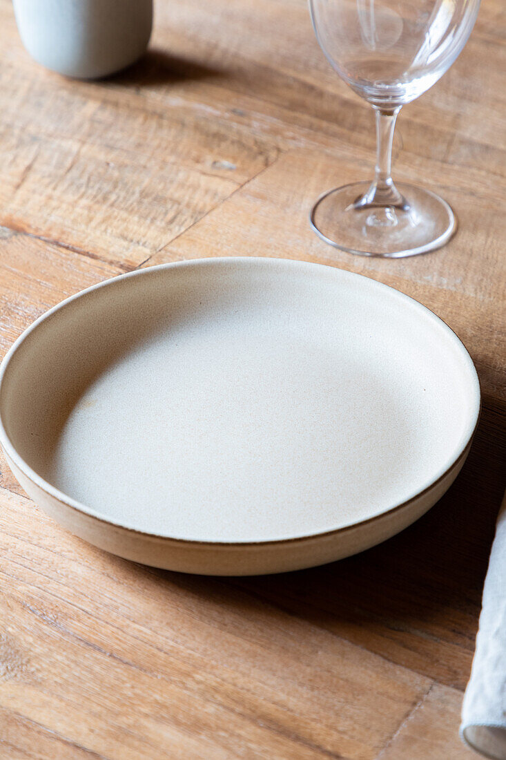 Served table with ceramic plates with cutlery on napkin near wineglasses and flowers with fruits