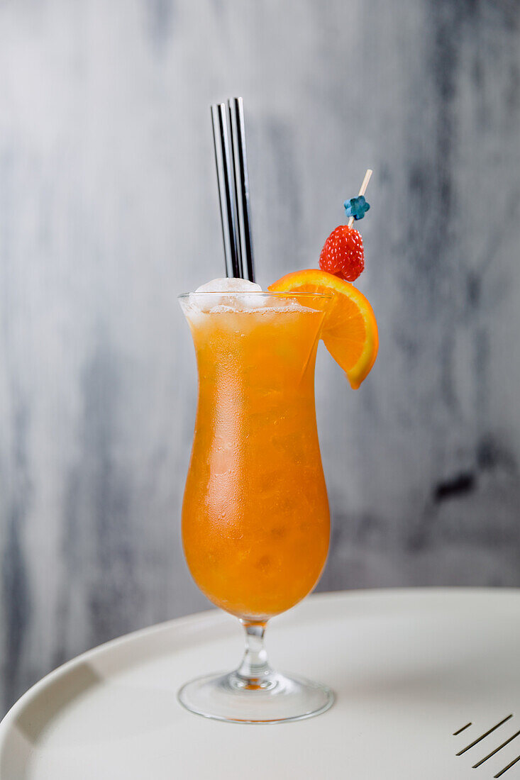 Glas mit kaltem Sex on Beach-Cocktail mit Wodka, Pfirsichlikör und Orangensaft mit Strohhalm und Eis