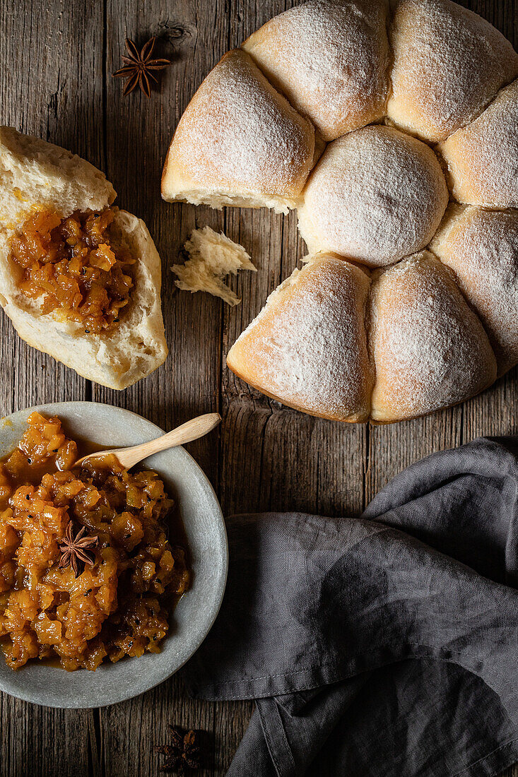 Top view of tasty homemade soft bread buns and sauce in plate served on wooden table with spoon