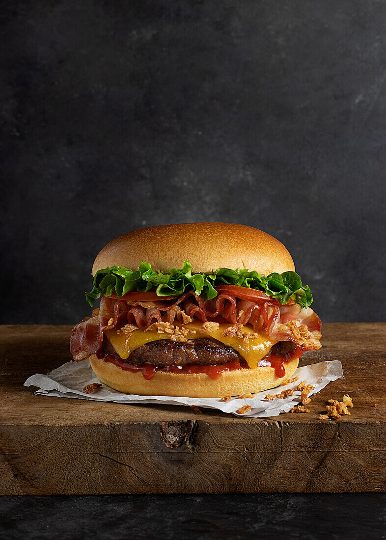 Detail of a delicious burger with cheese and bacon on the wooden table