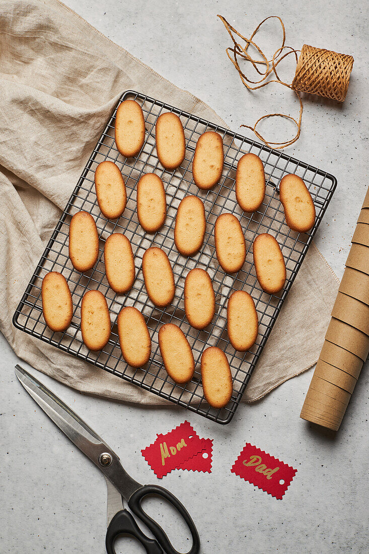 Leckere Weihnachtsplätzchen von oben auf einem Metall-Backnetz auf einem Tisch mit verschiedenen Verpackungsmaterialien