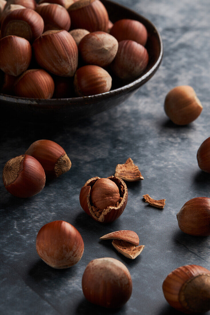 From above bunch of ripe hazelnuts in bowl and shells on marble table