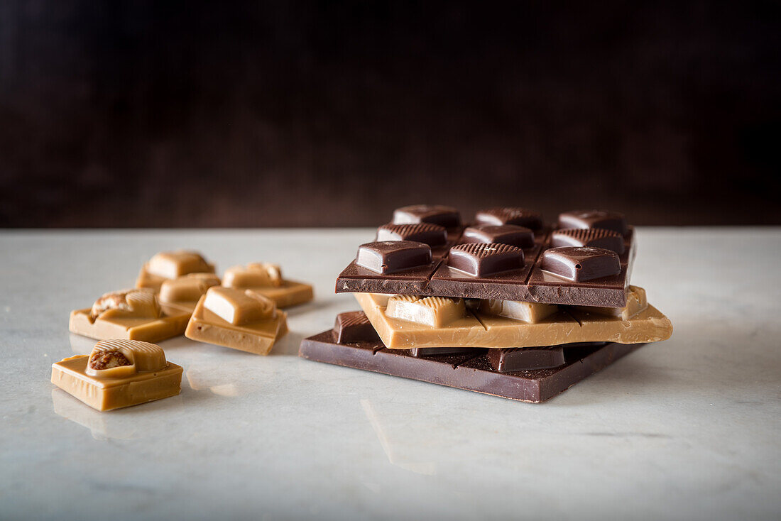 Köstliche Schokoladenbonbons mit herzförmigen Nüssen auf weißem Hintergrund verstreut