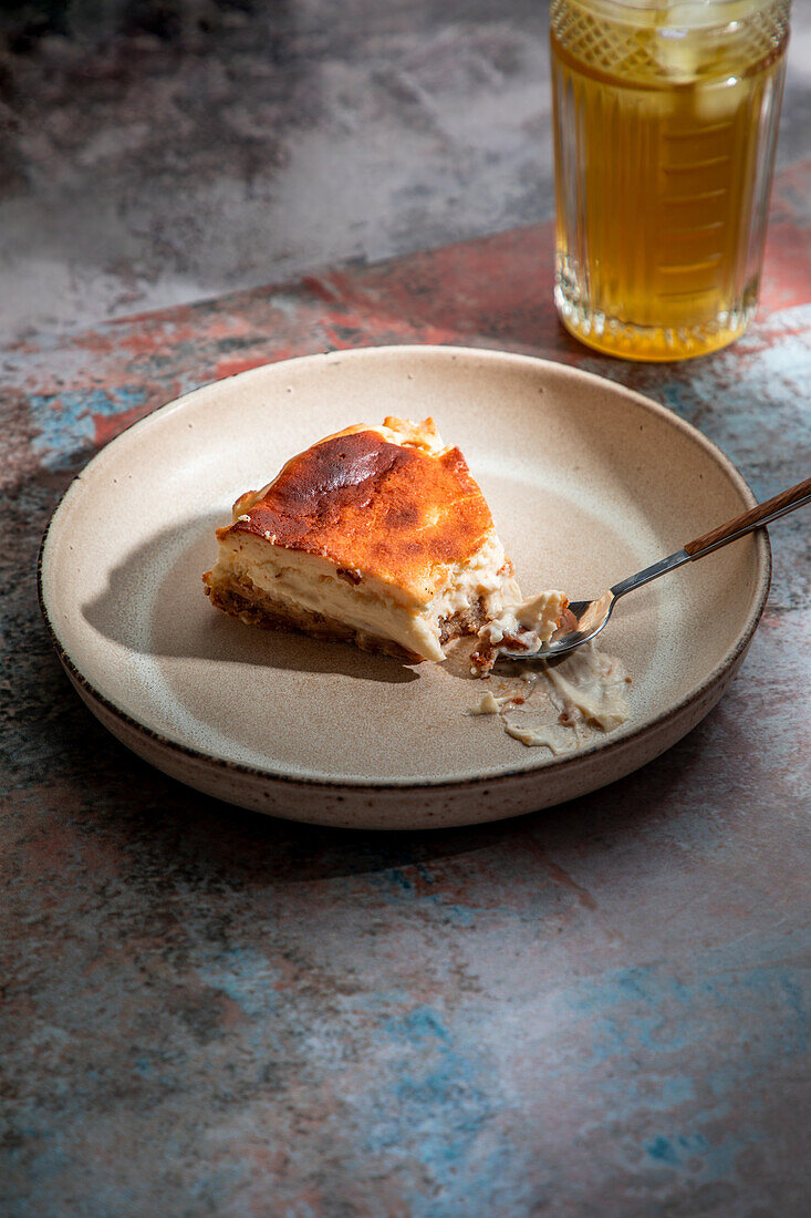 From above of appetizing pie placed on ceramic plate with glass of drink with ice in restaurant