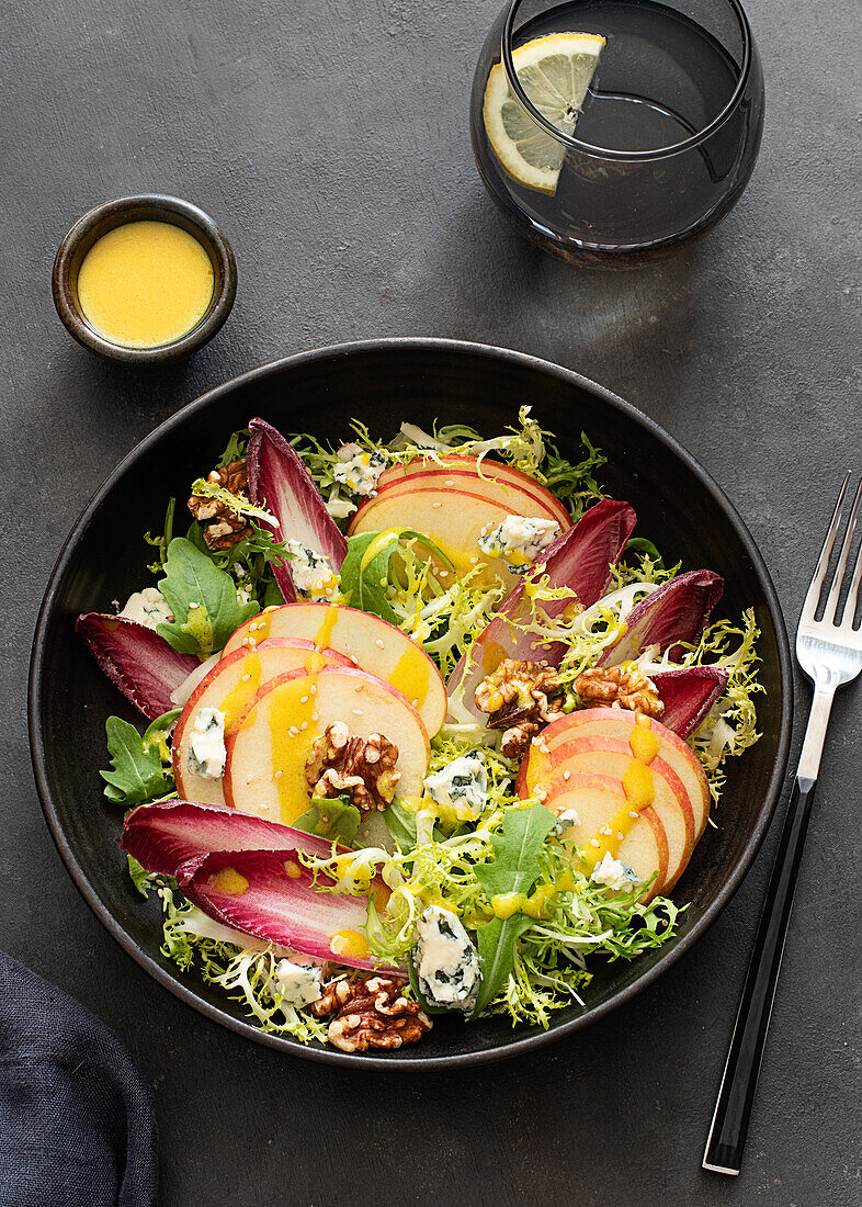 From above colorful delicious salad with endives, apple and roquefort cheese on dark background