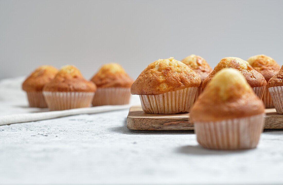 Leckere hausgemachte, frisch gebackene süße Muffins in Pappbechern auf dem Tisch angeordnet