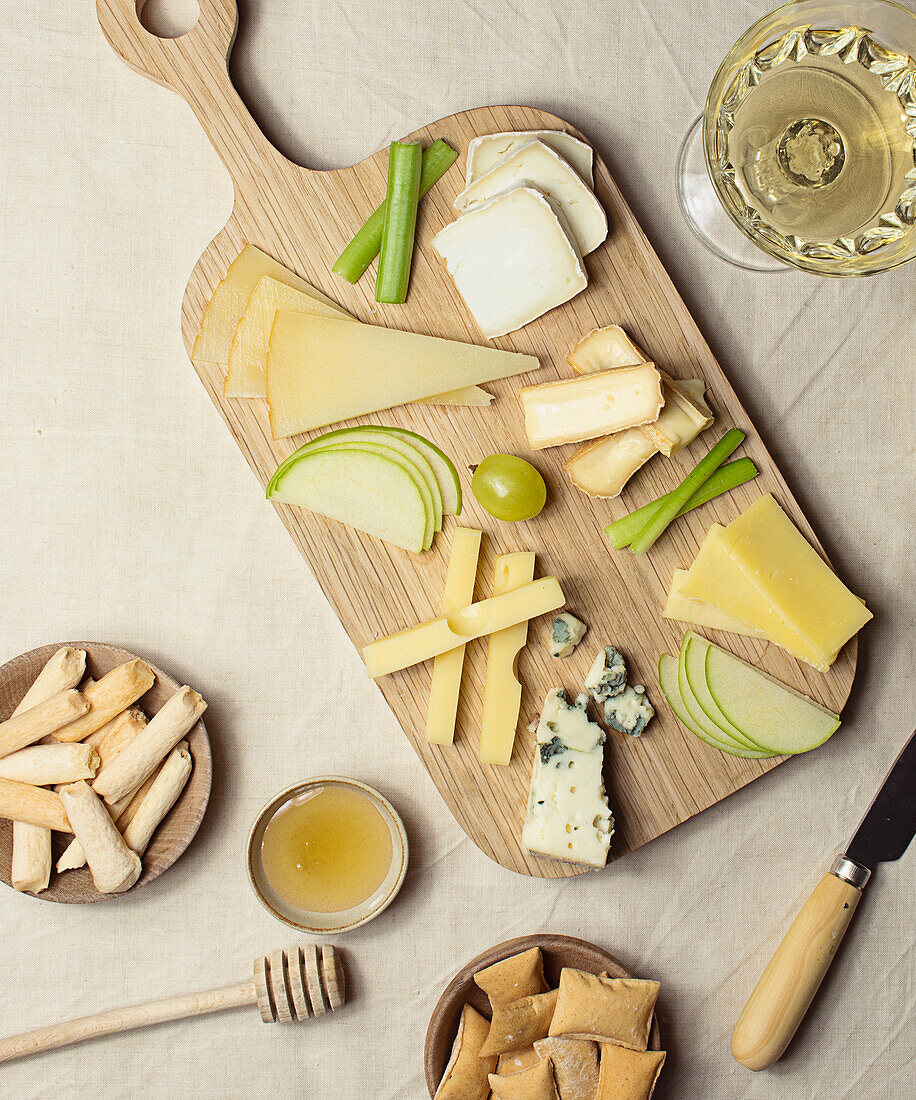 From above various cut cheese on wooden board with croutons placed on table