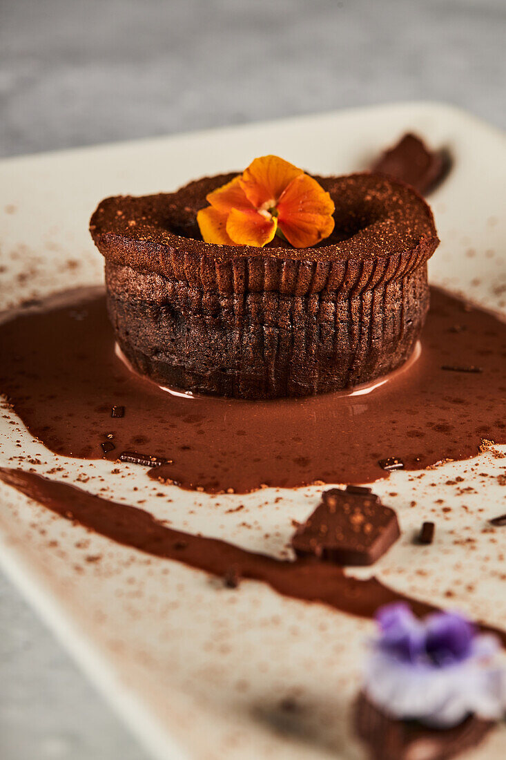 Leckerer Schokoladen-Coulant mit Orangenblüten garniert und auf einem Teller im Restaurant serviert