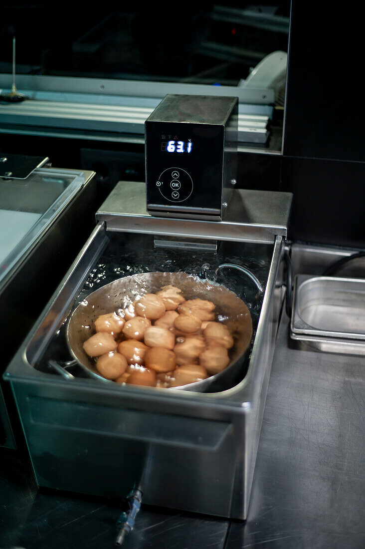 Chicken eggs cooking in sous vide with temperature controller on restaurant kitchen