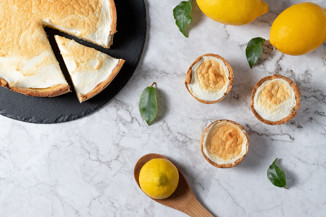 From above of sweet meringue pie and fresh lemons arranged on marble table in kitchen