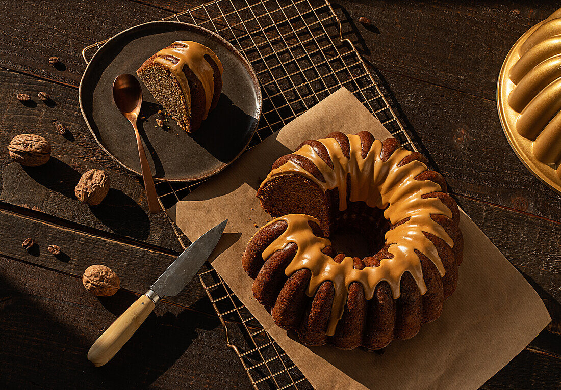 From above coffee walnut bundt cake placed on baking net on dark rustic wooden table in kitchen