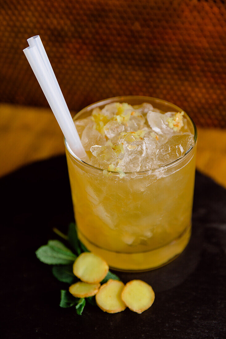Glass of sour Yuzu Spice cocktail made of alcohol and juice served with pieces of ginger