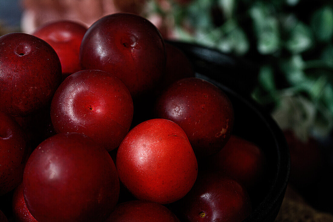 Bowl with fresh sweet plums served on black table