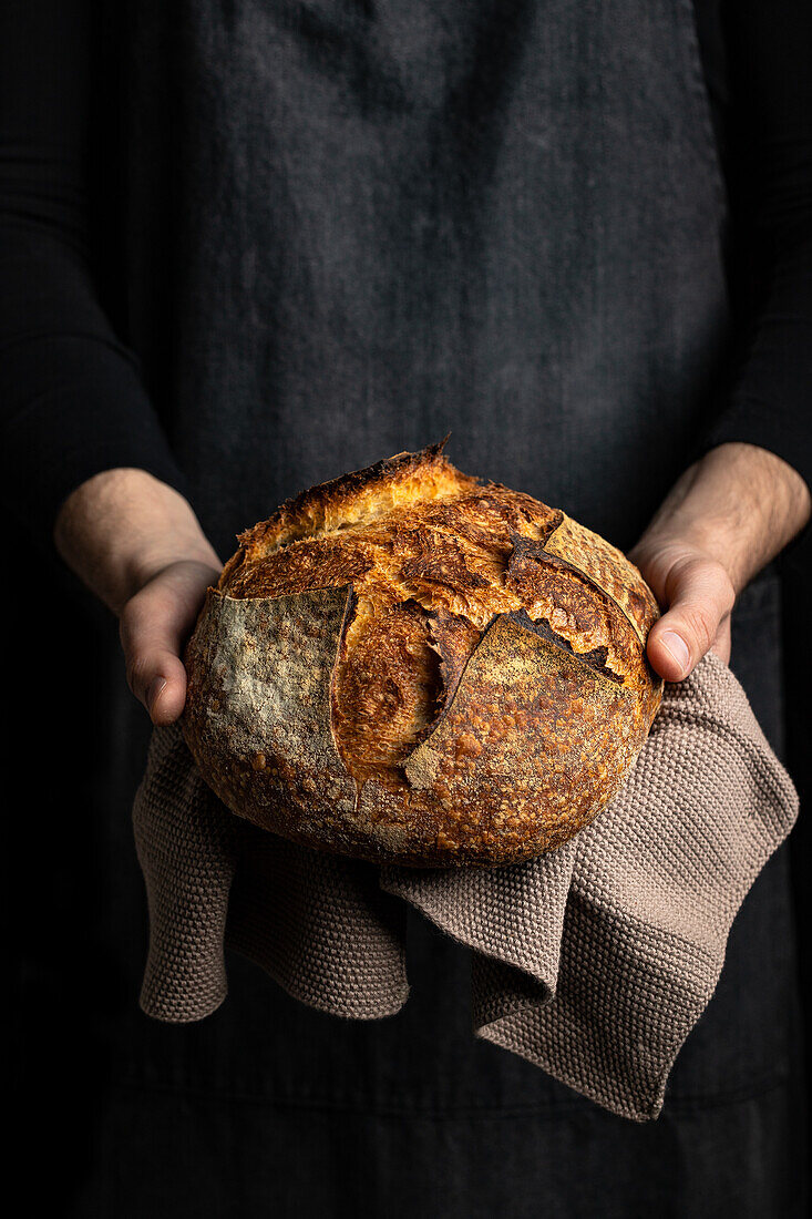 Unbekannter Erntekoch in Schürze steht mit einem Stück frisch gebackenen Brotes