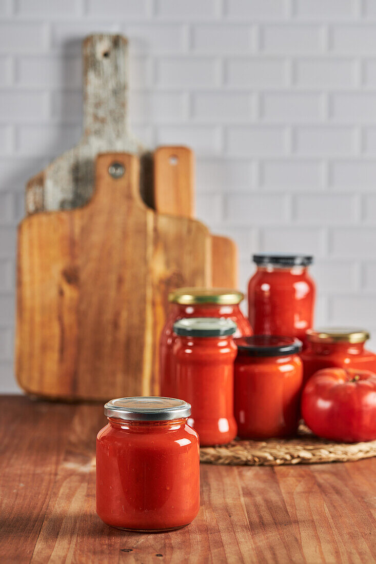 Sealed glass jar with handmade tomato sauce placed on table in kitchen at home