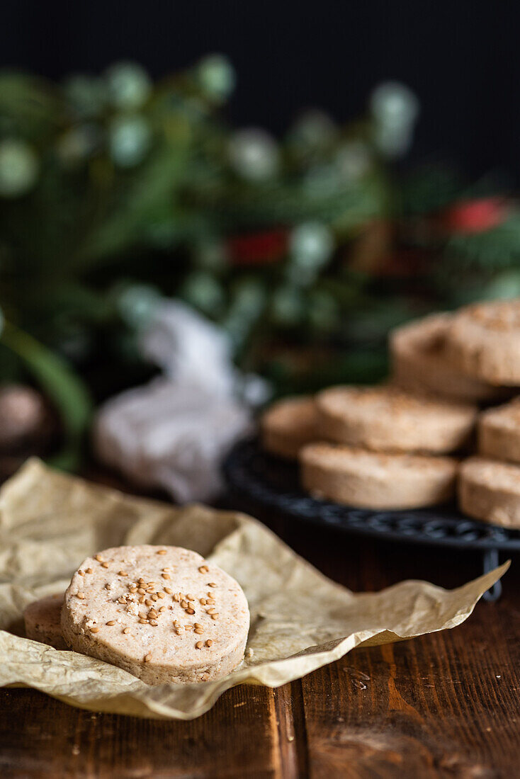 Pile of appetizing sweet shortbread cookies with hazelnuts served on plate on wooden table with festive wrapping paper and ribbons for Christmas celebration