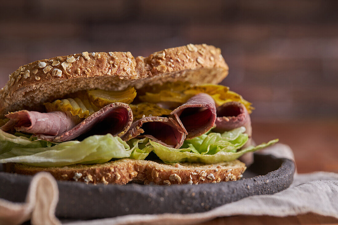 Closeup of a delicious pastrami, lettuce, ham and pickle sandwich