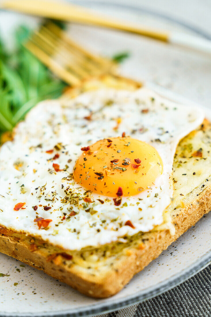 Toast with eggs and cheese and rocket lettuce served on plate on table background