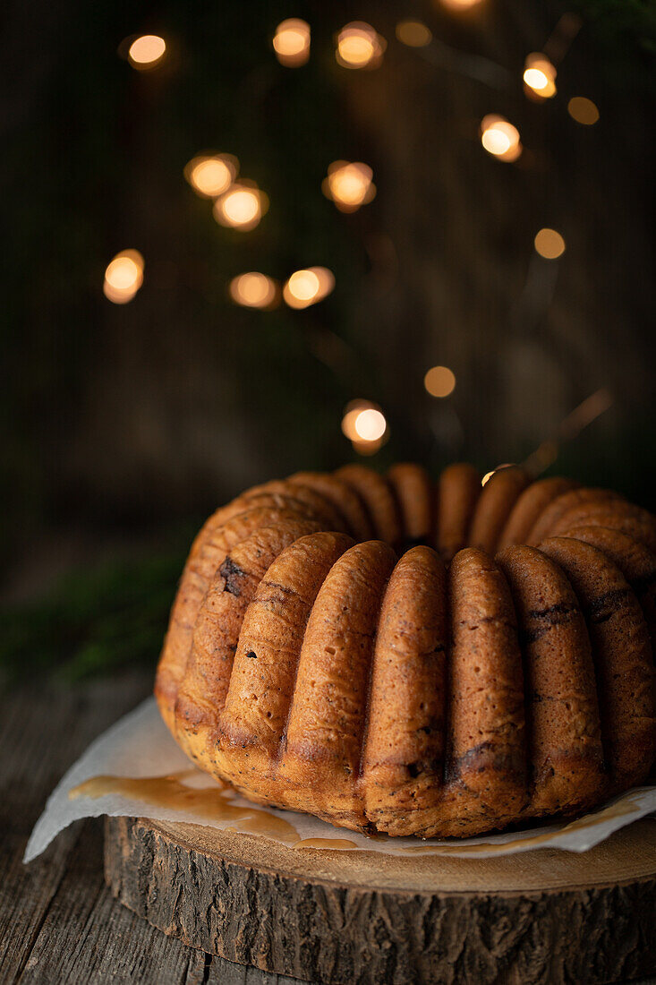 Delicious homemade chocolate cake on wooden trunk tray against black background with fairy lights