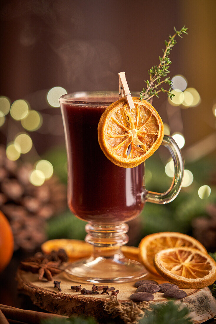 Glühwein oder Weihnachtspunsch, serviert in einem Glasbecher mit getrockneten Orangenscheiben