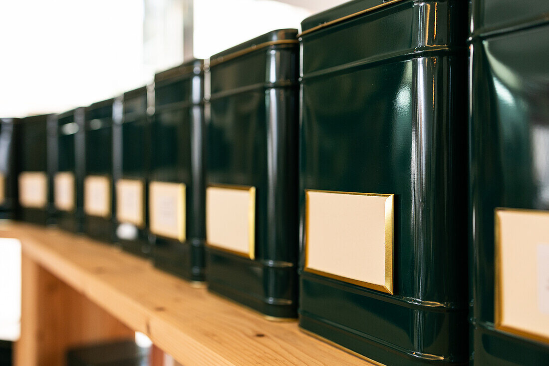 Moderne schwarze Behälter in einer Reihe auf einem Holzregal in einem Geschäft mit leeren Etiketten
