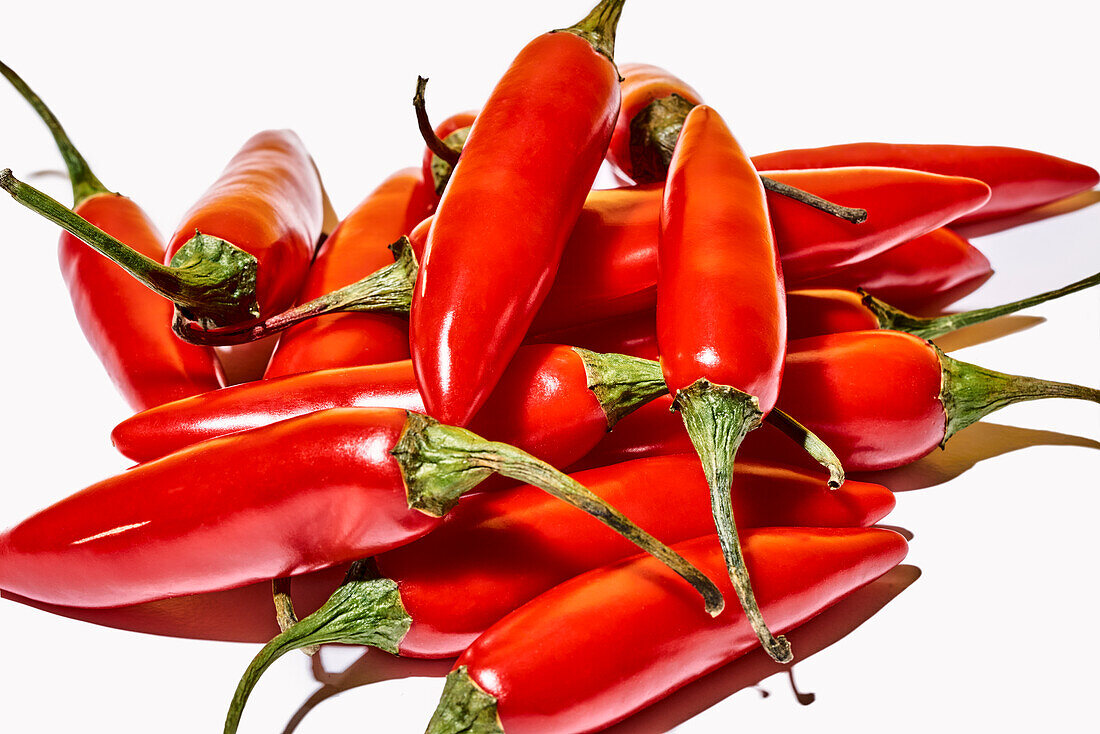 Top view composition with red fresh exotic peppers used as spice or condiment to flavor food on white background