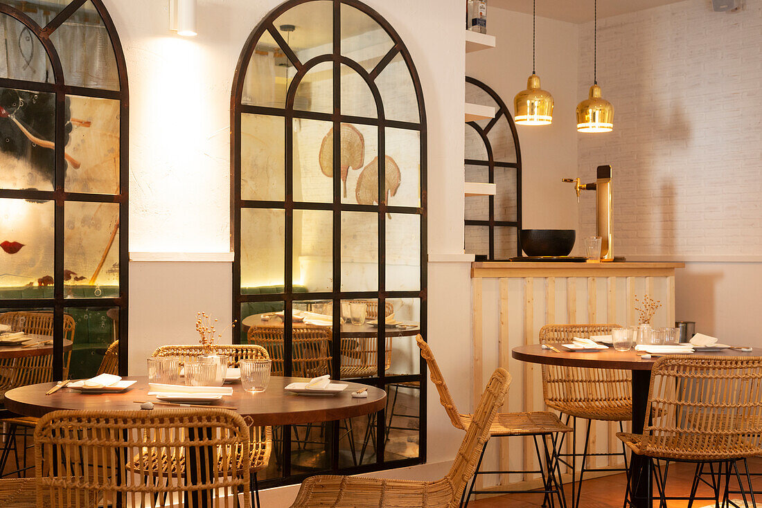 Holztische und Korbstühle in einem gemütlichen, geräumigen Restaurant mit modernem Interieur