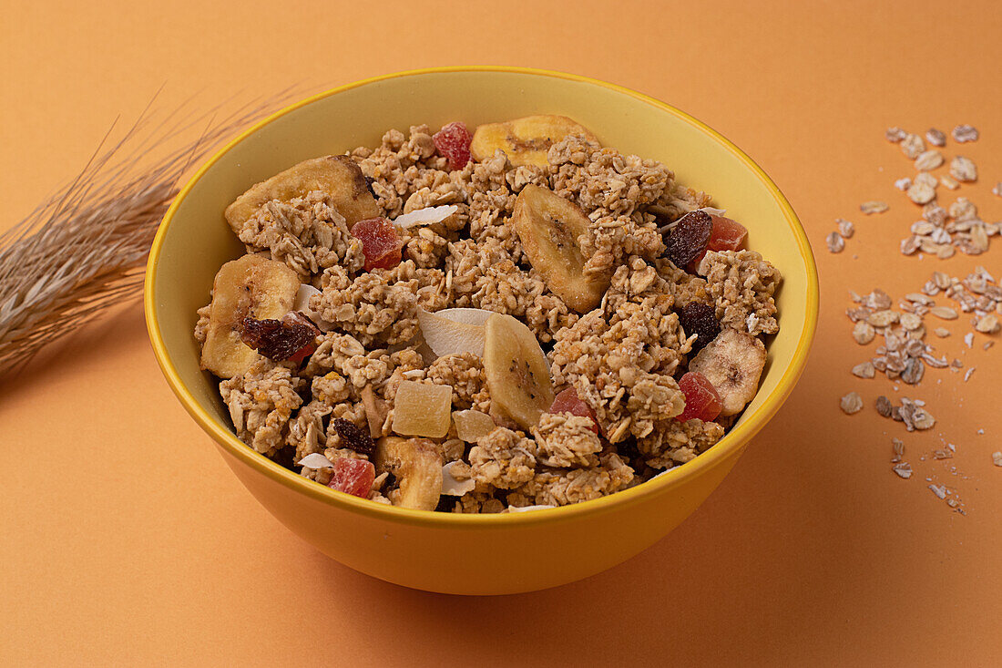 From above crispy granola with dried fruits in bowl on light table brown background