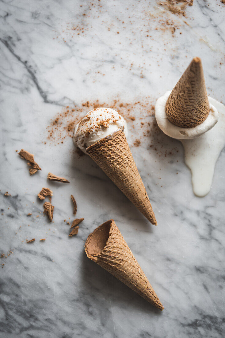 Overhead view of tasty waffle cones with creamy meringue milk gelato scoops on marble table