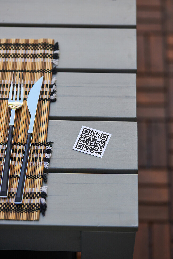 Hoher Winkel des QR-Codes einer Speisekarte eines asiatischen Restaurants auf einem Tisch mit Serviette, Messer und Gabel