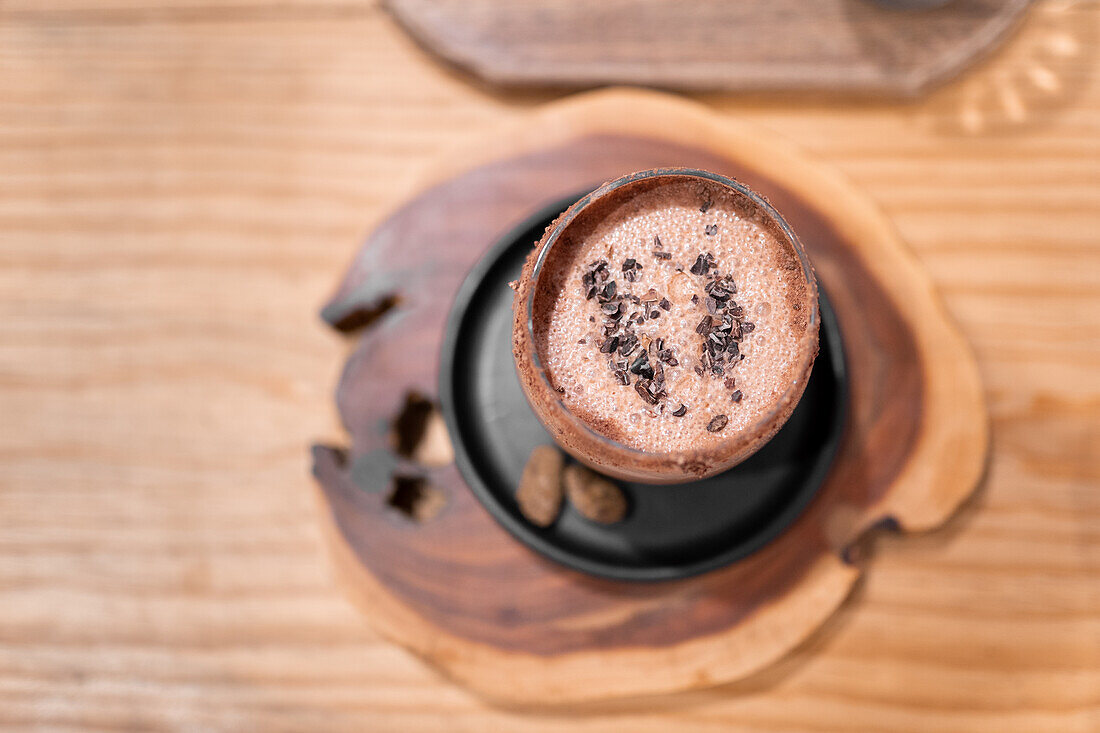 From above glass cup of traditional Mexican Champurrado drink placed on wooden slab on cafe table