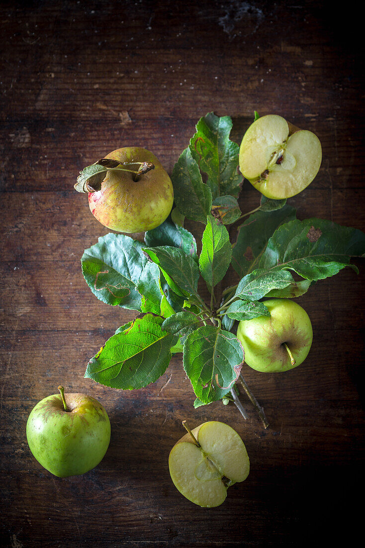 Top view of sweet ripe green apples arranged with leaves on rustic wooden table