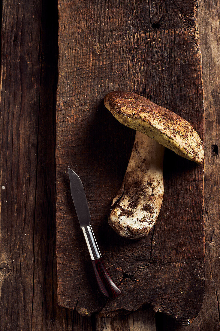 Draufsicht auf roh geschnittene Steinpilze (Boletus edulis) auf rustikalem Holzschneidebrett während des Kochvorgangs