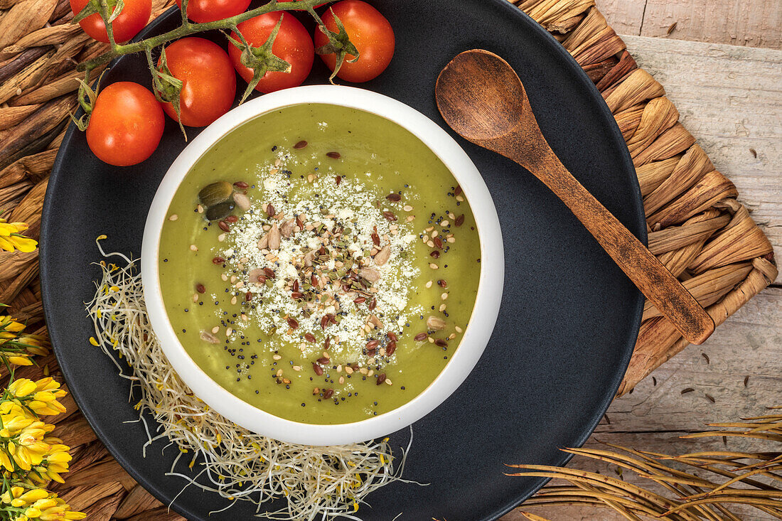 From above of yummy puree soup with crushed pistachios and seasonings near ripe cherry tomatoes
