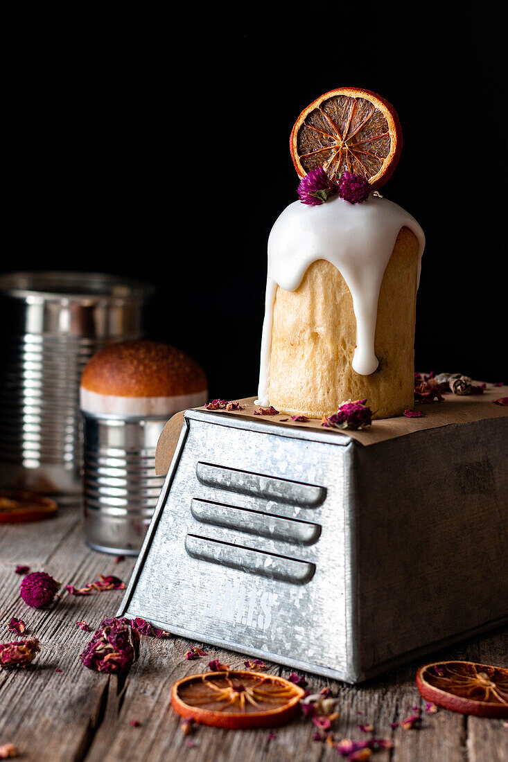 Several delicious homemade kulichs poured with sweet glaze and decorated with pieces of dry orange and flowers on wooden table