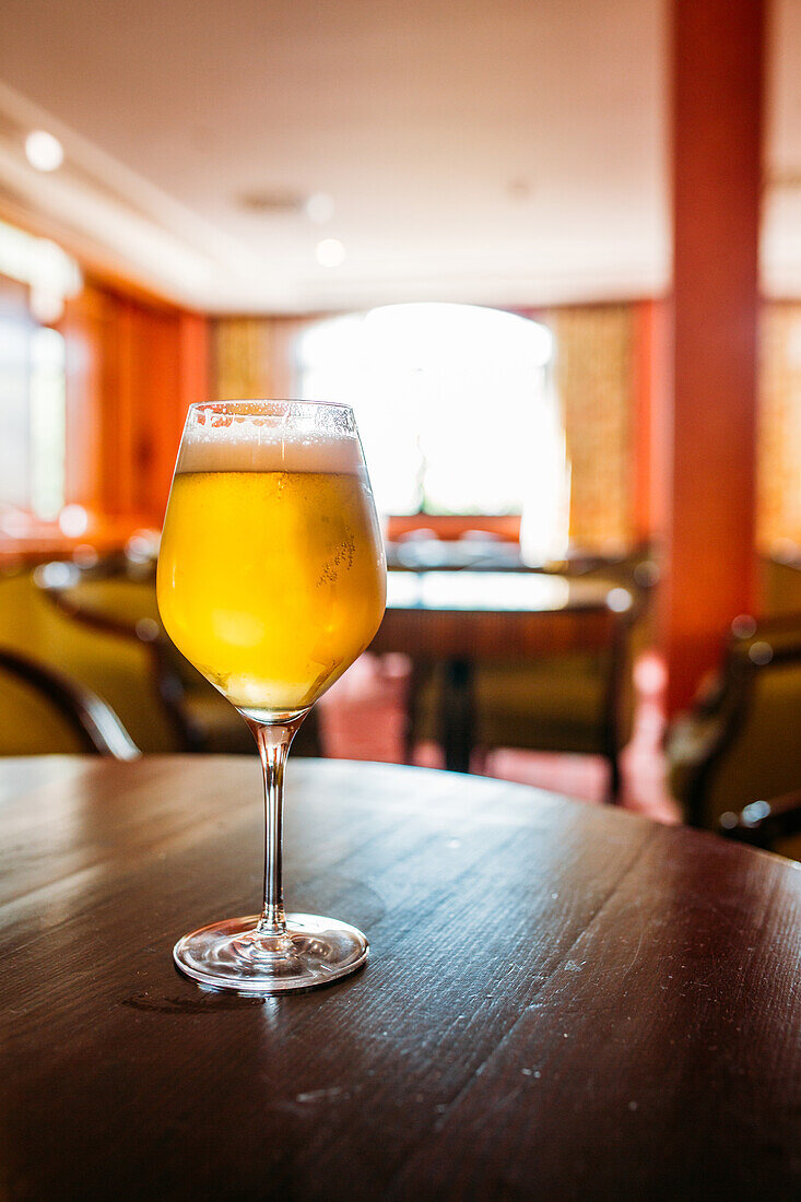 Glass of beer in a wooden table in a pub against blurred background