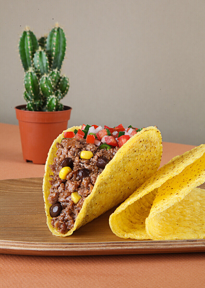 Mince meat tacos with corn and sauce on wooden tray