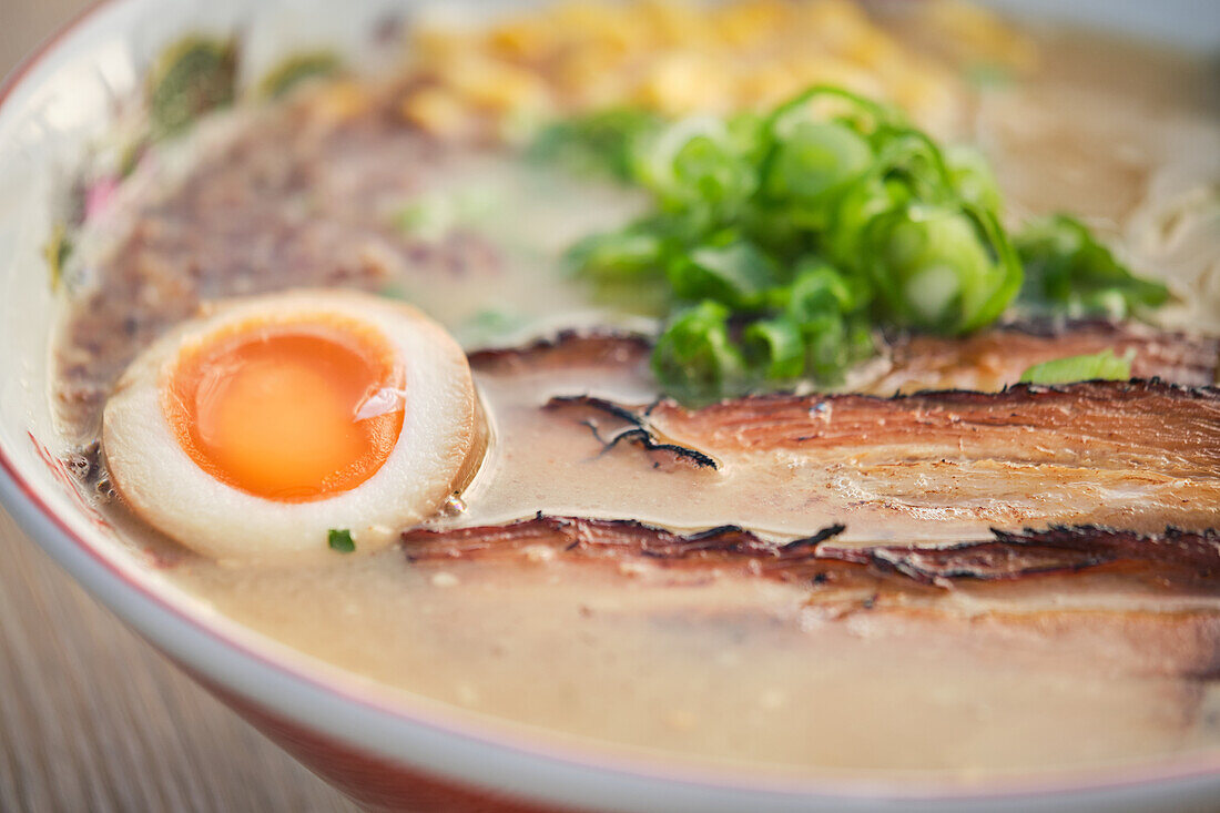 Stockfoto von leckerer Ramen-Suppe mit gekochtem Ei und Fleisch in einem japanischen Restaurant, bereit zum Servieren
